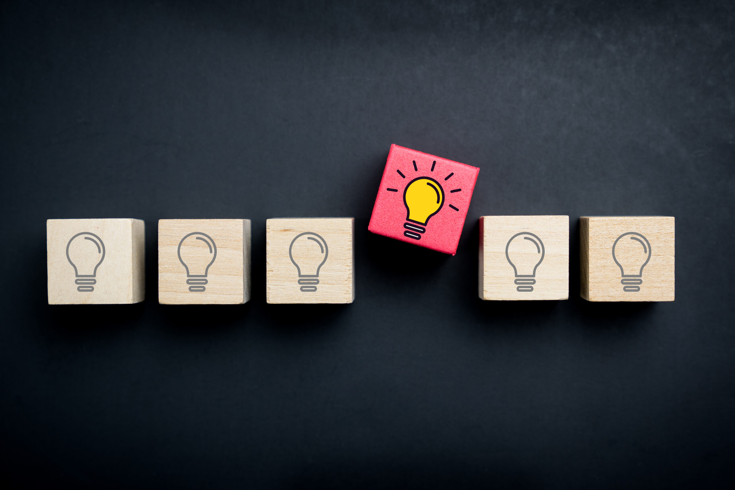 Innovation and creative idea concept blocks with lightbulbs on them with one that stands out from the rest to conceptualize creativity and innovation